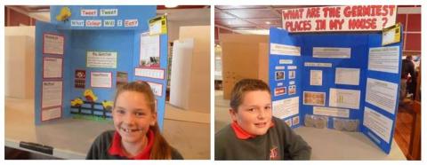 Two students with their completed science investigations on a display boards