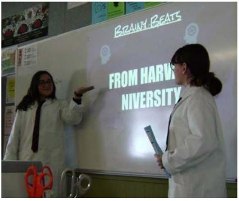 Two students sharing their findings from project-based learning on a whiteboard